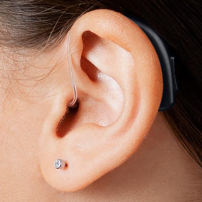 A discreet hearing aid behind the ear, almost invisible